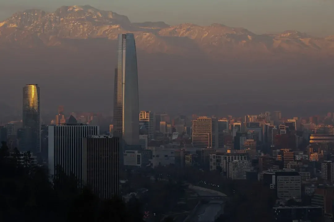 A warm wide illustration of Santiago at golden hour, the Andes glowing pink behind the Costanera Center tower, Parque Bicentenario green in the foreground.
