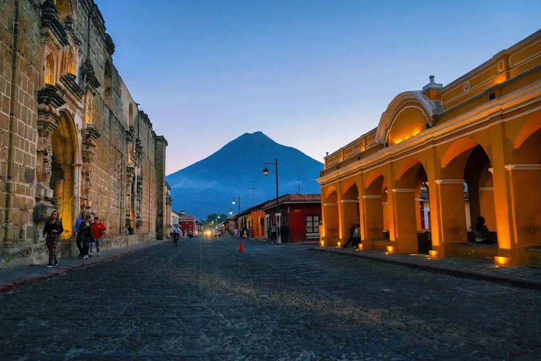 A warm illustration of Quito at golden hour, the historic centre domes and red rooftops below the green Pichincha volcano under a clear amber sky.