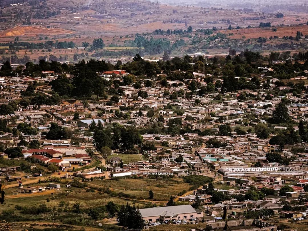 A contractor working at an outdoor desk in Mbabane, Eswatini, with the Mdimba Mountains visible in the background and warm afternoon light across the Hhohho hills.