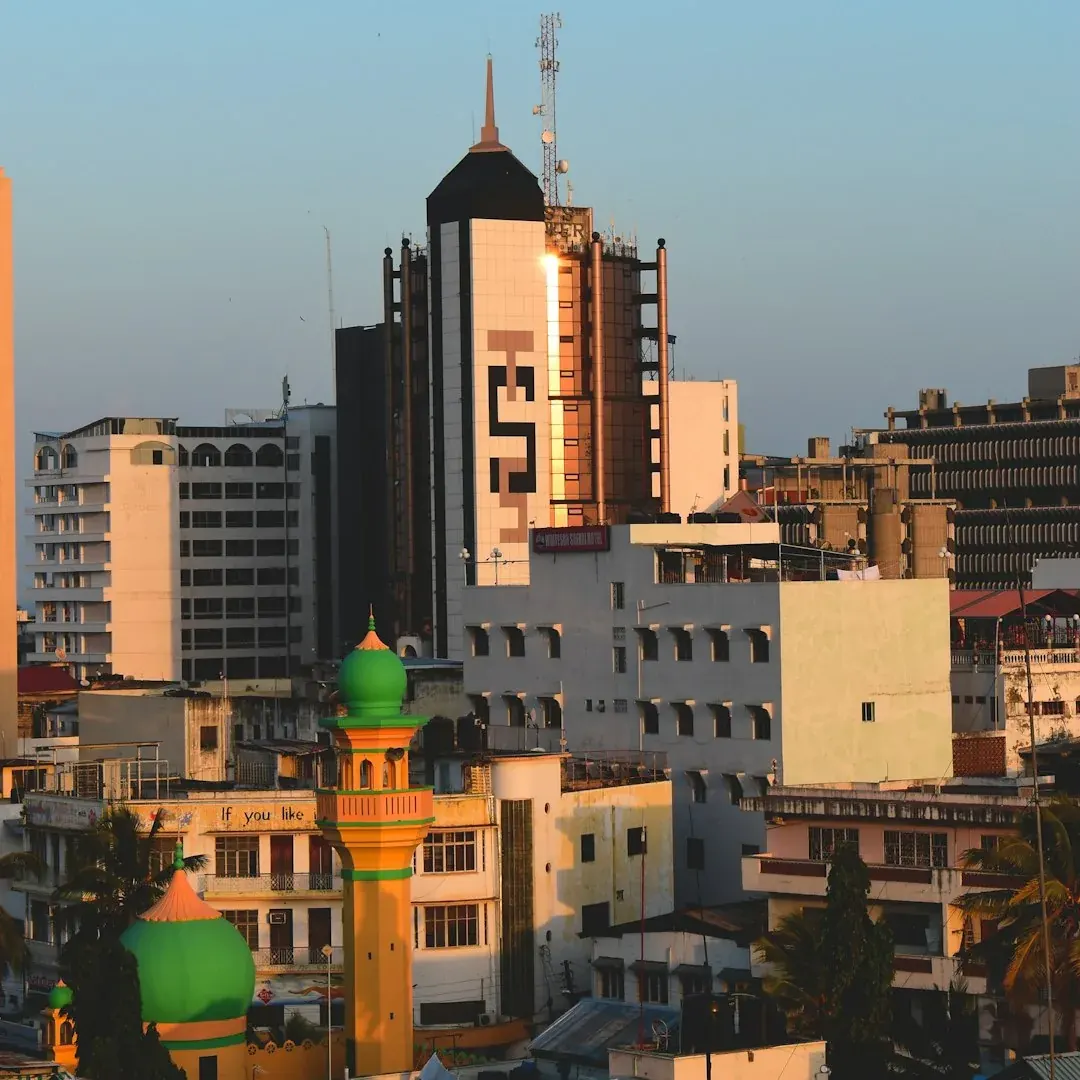 A wide illustration of Nairobi at golden hour: the city skyline with the CBD towers visible, a clear amber sky above, and the green Uhuru Park in the foreground.