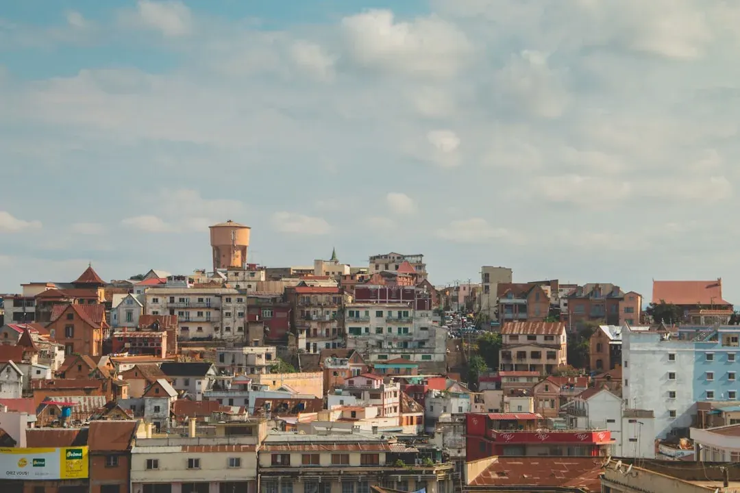 A contractor in Madagascar working at an outdoor table in Antananarivo, with the terracotta rooftops of the old town and the Rova citadel visible in the background.