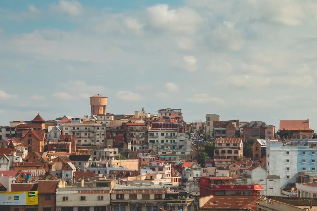 A contractor in Madagascar working at an outdoor table in Antananarivo, with the terracotta rooftops of the old town and the Rova citadel visible in the background.