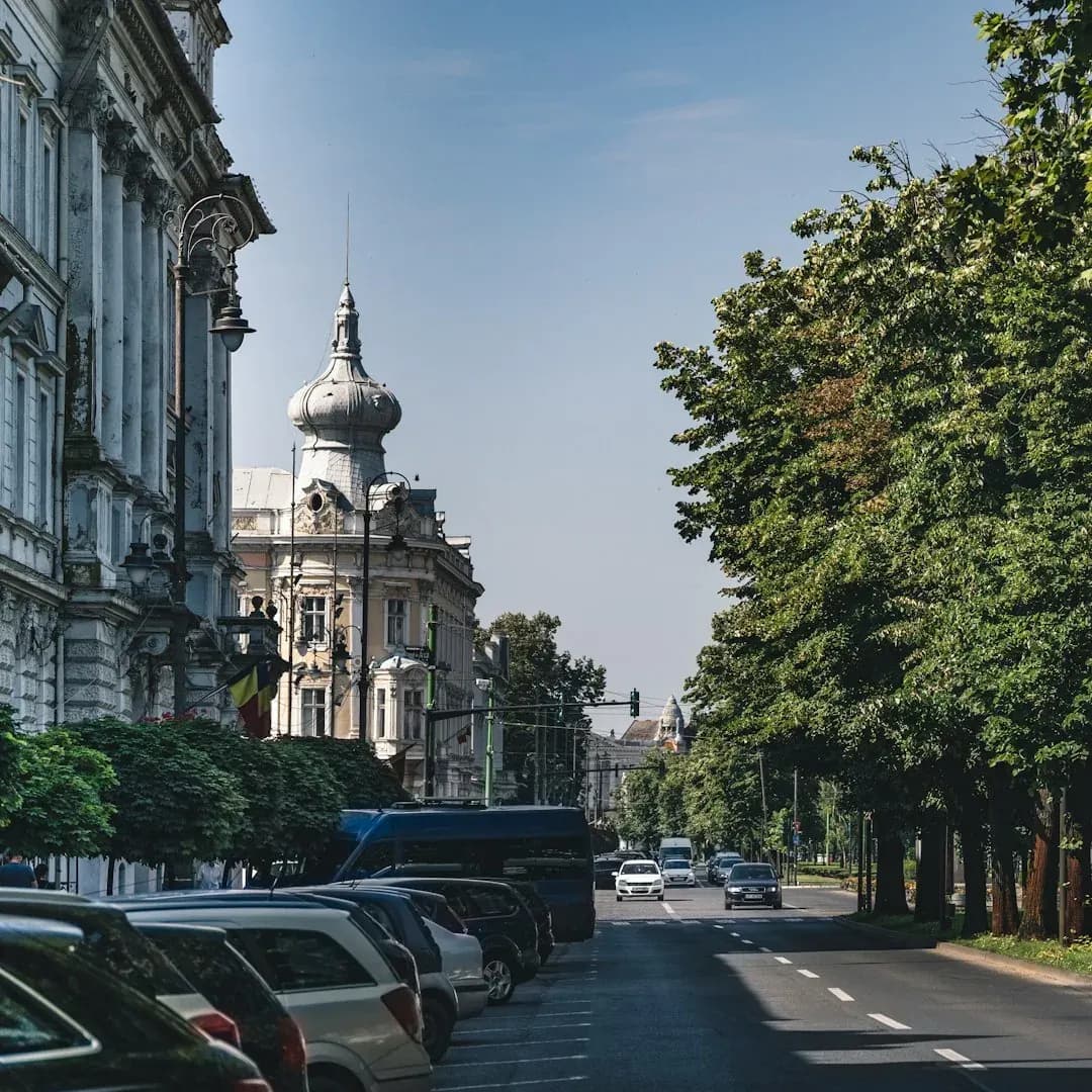 A wide illustration of Bucharest at golden hour: the Palace of the Parliament in the foreground, tree-lined boulevards stretching behind it, and a clear amber sky above the city.
