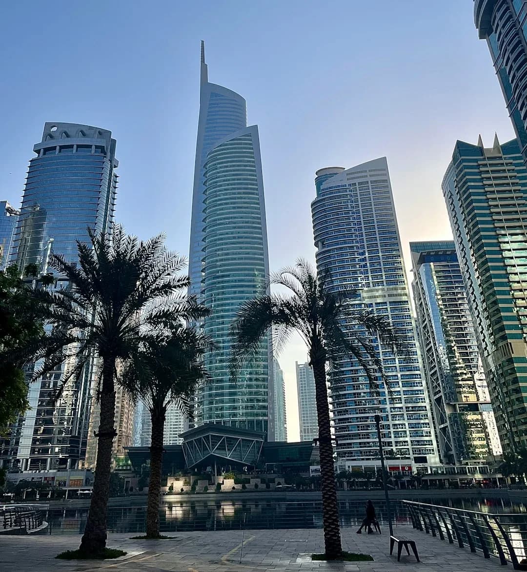 A wide illustration of Dubai at golden hour: the Burj Khalifa rising above a modern skyline, Sheikh Zayed Road stretching through the city, and a warm amber sky above the Arabian Gulf.