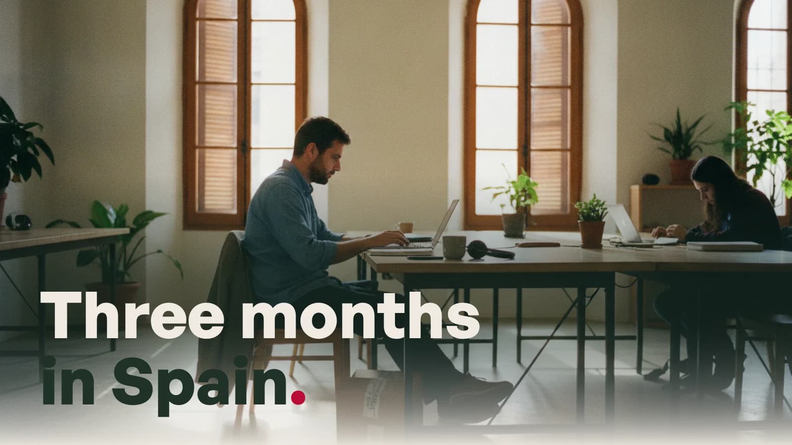 A man working at a shared desk in a bright Spanish office, with the line Three months in Spain.