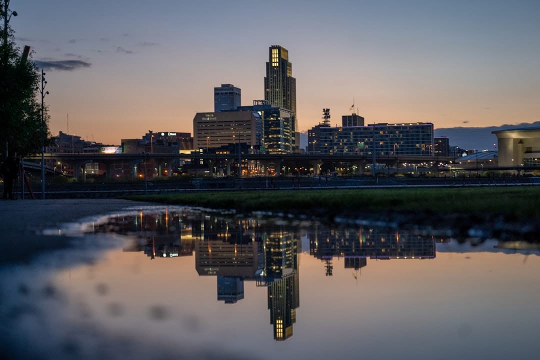Omaha, Nebraska downtown skyline reflected in the Missouri River at dusk, city towers catching amber light.