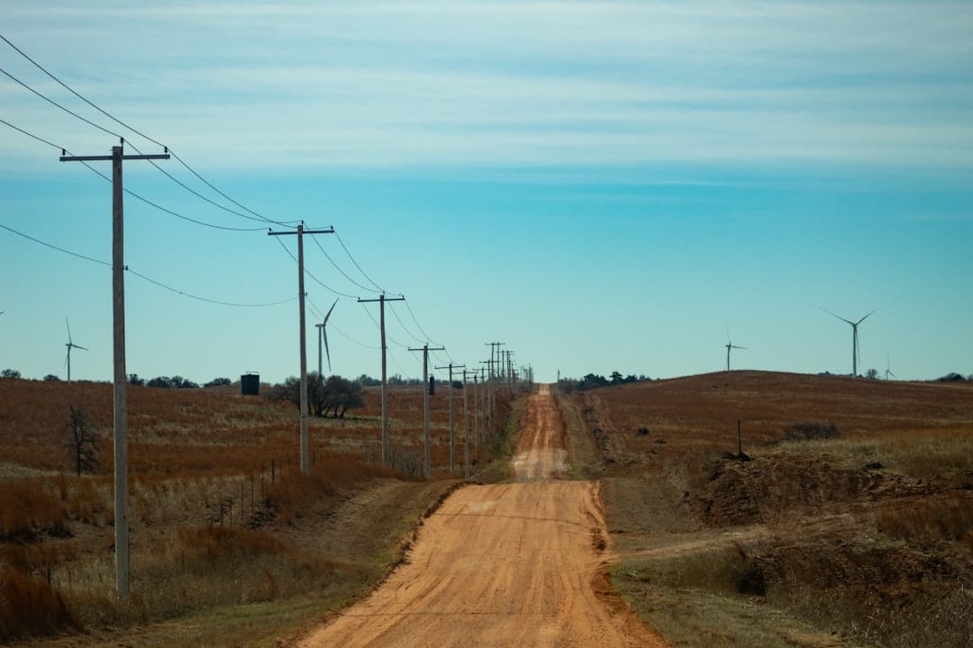 Midwest prairie road with power lines and windmills stretching to the horizon.