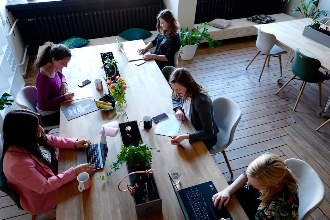 Team of people working together around a table in a bright coworking space.