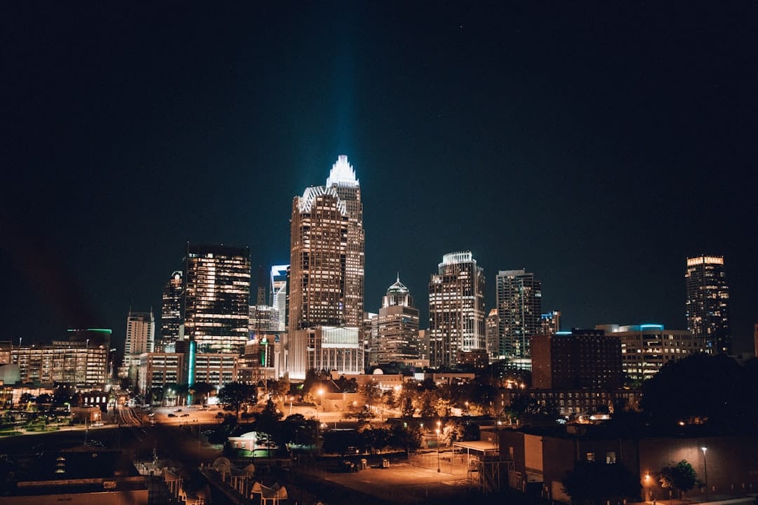 Charlotte, North Carolina skyline at dusk, city lights reflecting off the buildings.