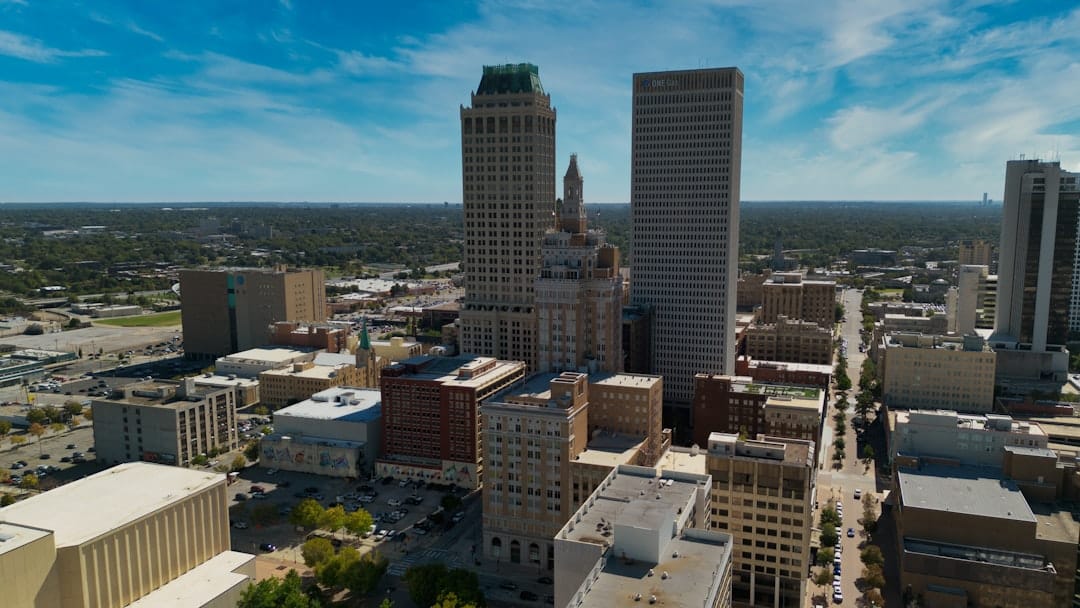Oklahoma City business district at midday, modern glass towers rising above the central streets under a clear blue sky.