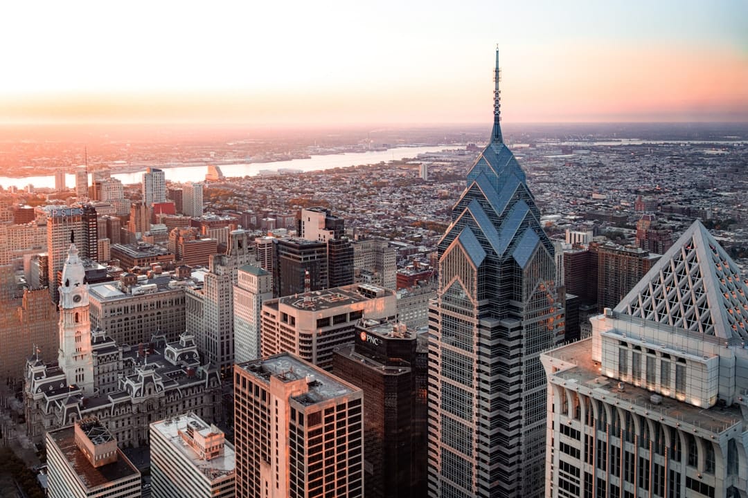 Philadelphia skyline at dawn, warm amber morning light over the city of brotherly love, urban architecture reflected in calm water