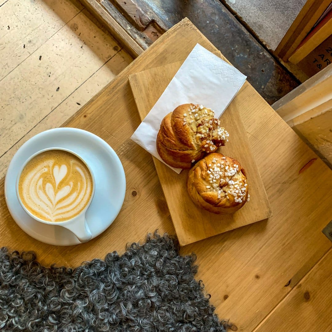 A cosy New England cafe with wooden tables, warm lighting, and fresh pastries at the counter.