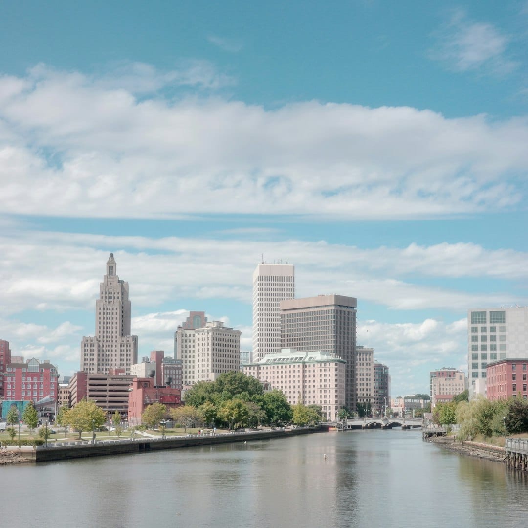 The Providence waterfront at golden hour, boats on the water below the city skyline.