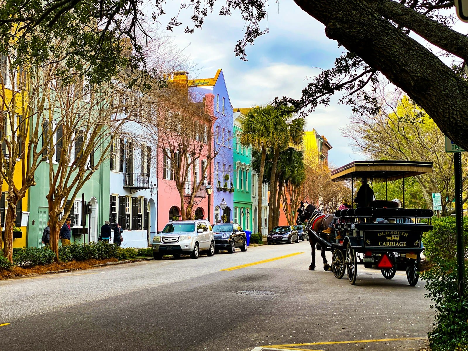 Charleston, South Carolina, historic street with horse-drawn carriage and antebellum buildings in warm afternoon light.