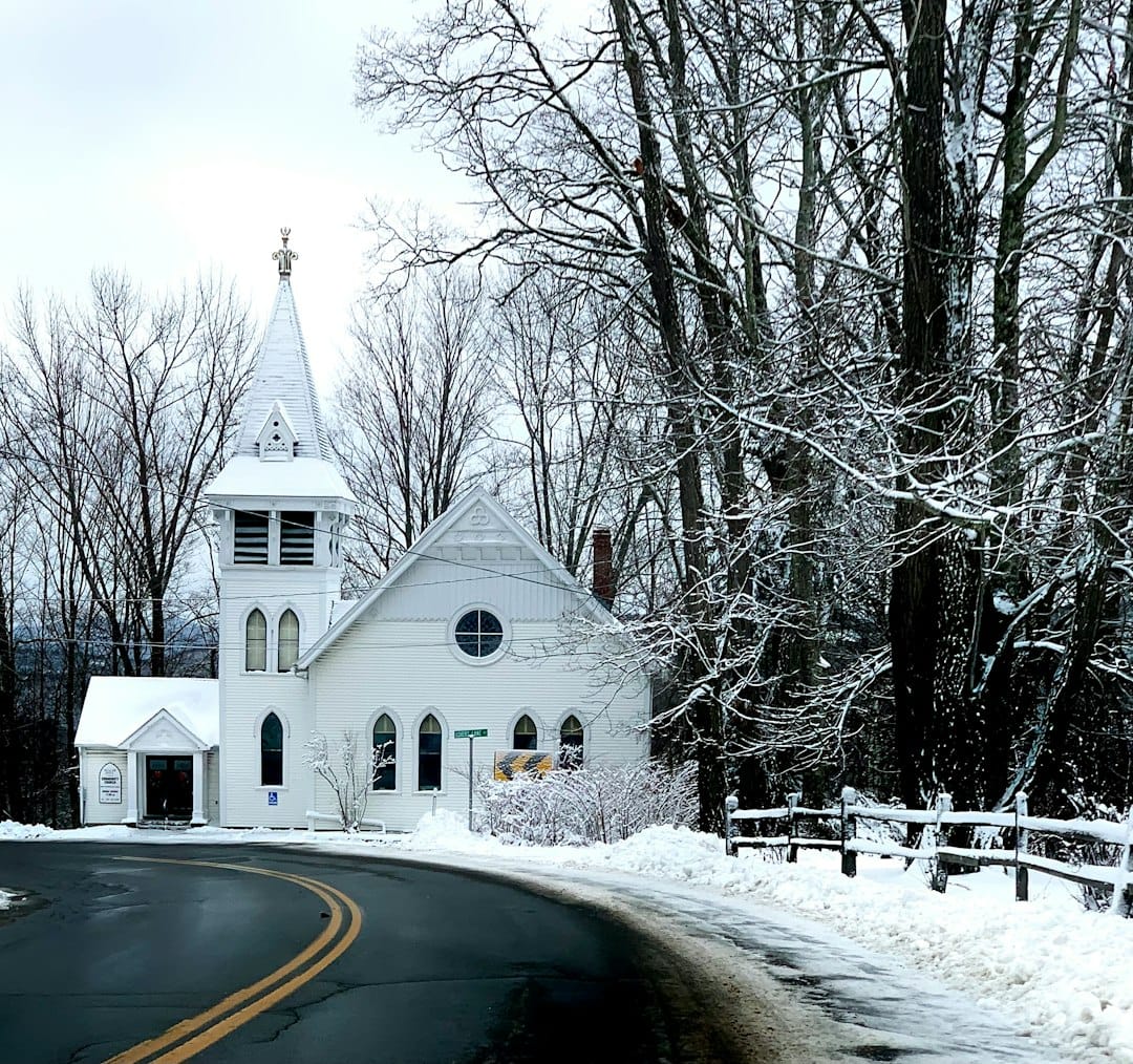 A New England town in winter, white-steepled church and snow-covered green, rural charm.