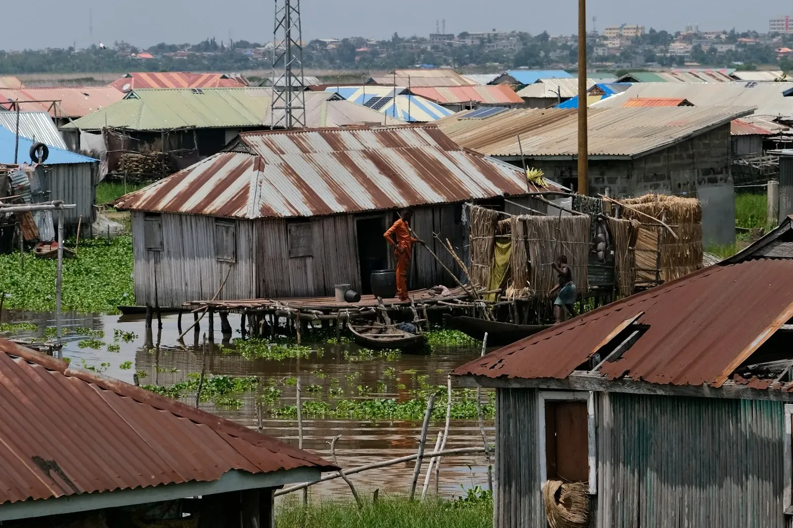Tin-roofed wooden houses on stilts above green water in the floating village of Ganvié on Lake Nokoué, Benin.