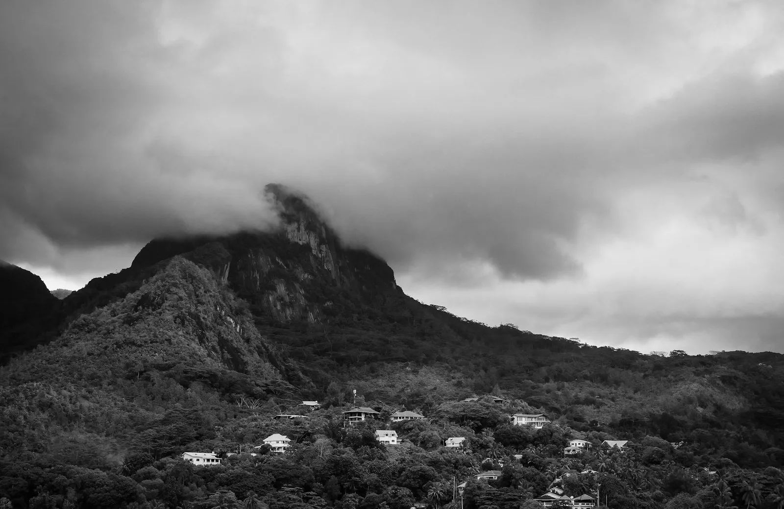 A dark grey mountain on Mahe rising into low cloud, in a black and white photograph.