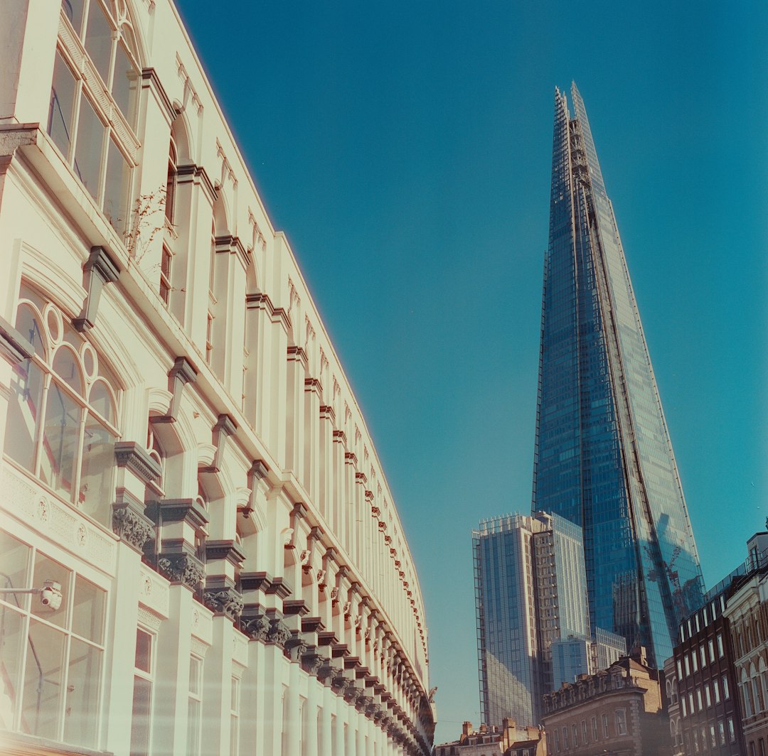 The Shard, London's tallest building, rising above a Georgian terrace against blue sky.
