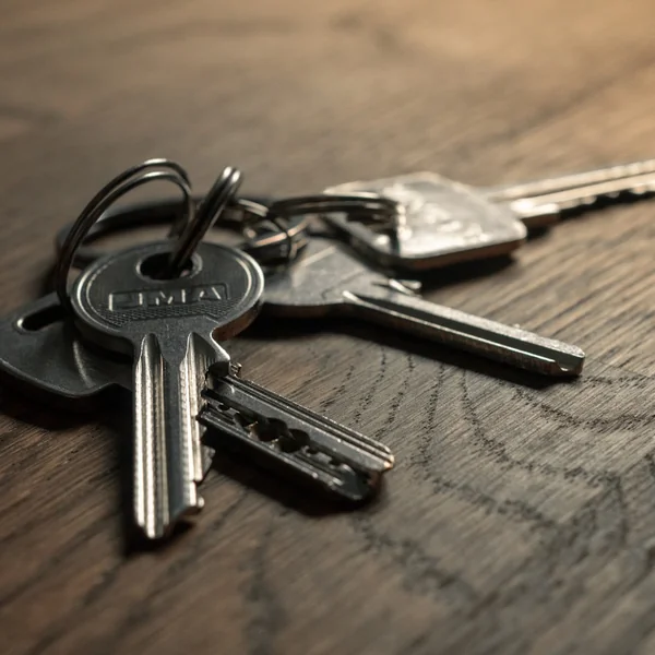 A bunch of keys on a wooden desk.