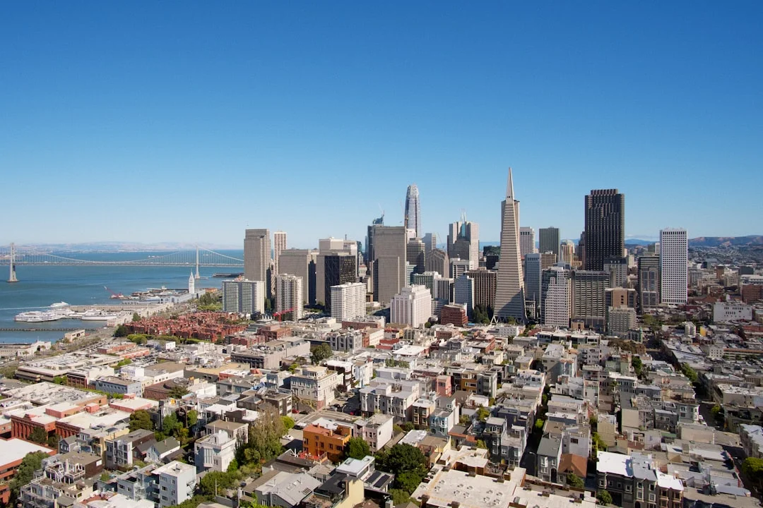 San Francisco financial district skyline under clear blue sky, mid-rise and high-rise office buildings visible from elevated vantage.