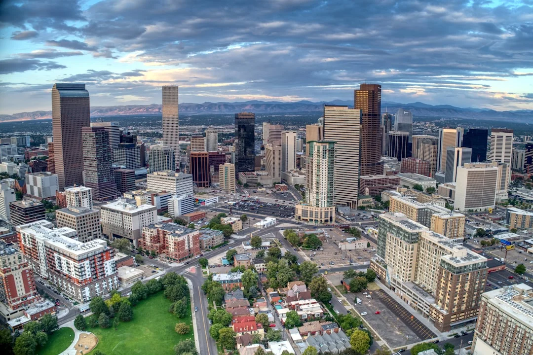 Aerial daytime view of downtown Denver, Colorado, with city buildings stretching toward the foothills.