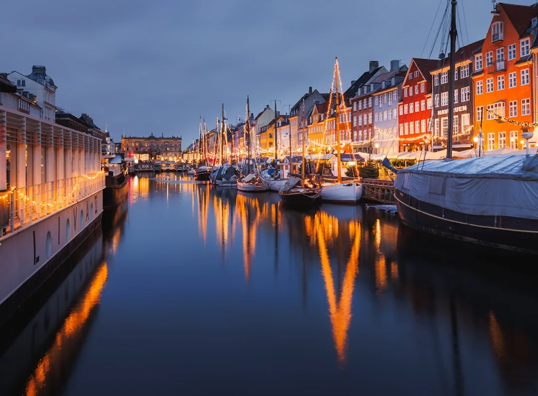 Copenhagen harbour at golden hour with the colourful Nyhavn townhouses reflected in the calm water.