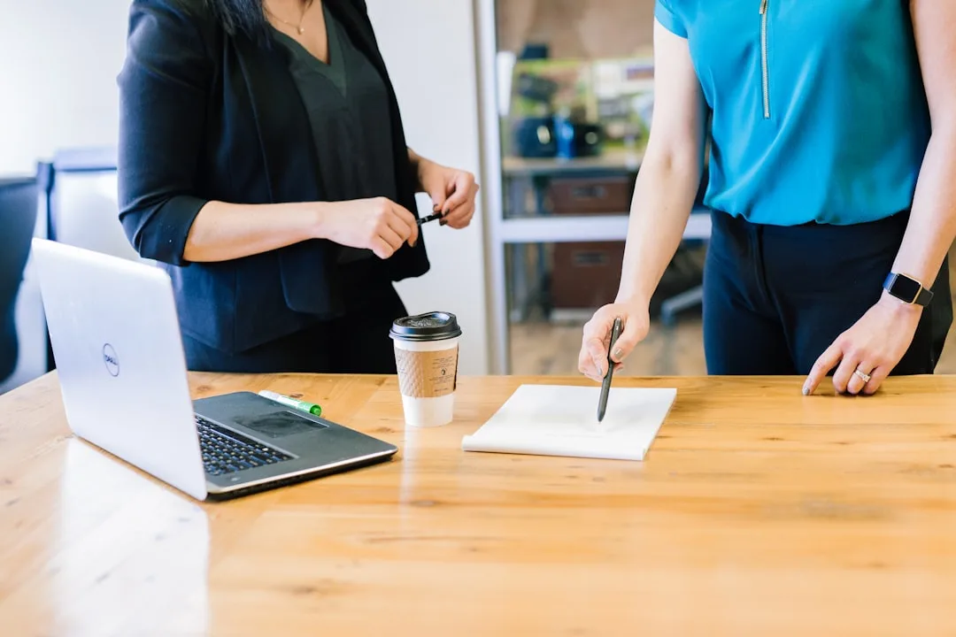Two colleagues comparing a printed employment contract at a bright wooden desk in a Copenhagen office.