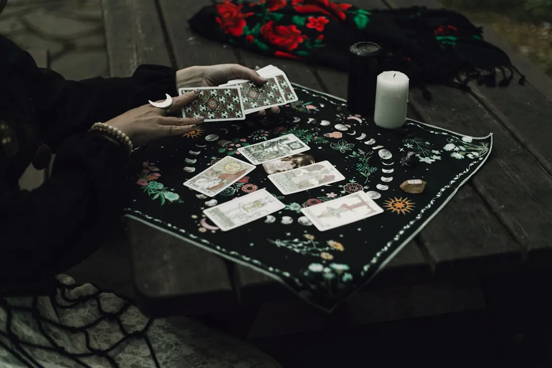 A hand sorting Danish krone banknotes beside a payslip on a pale wooden desk.