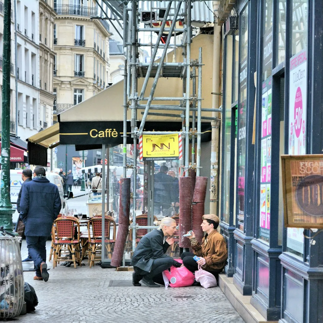 A freelancer working at a laptop in a sunlit cafe near the Canal Saint-Martin in Paris, with a coffee and notebook on the table.