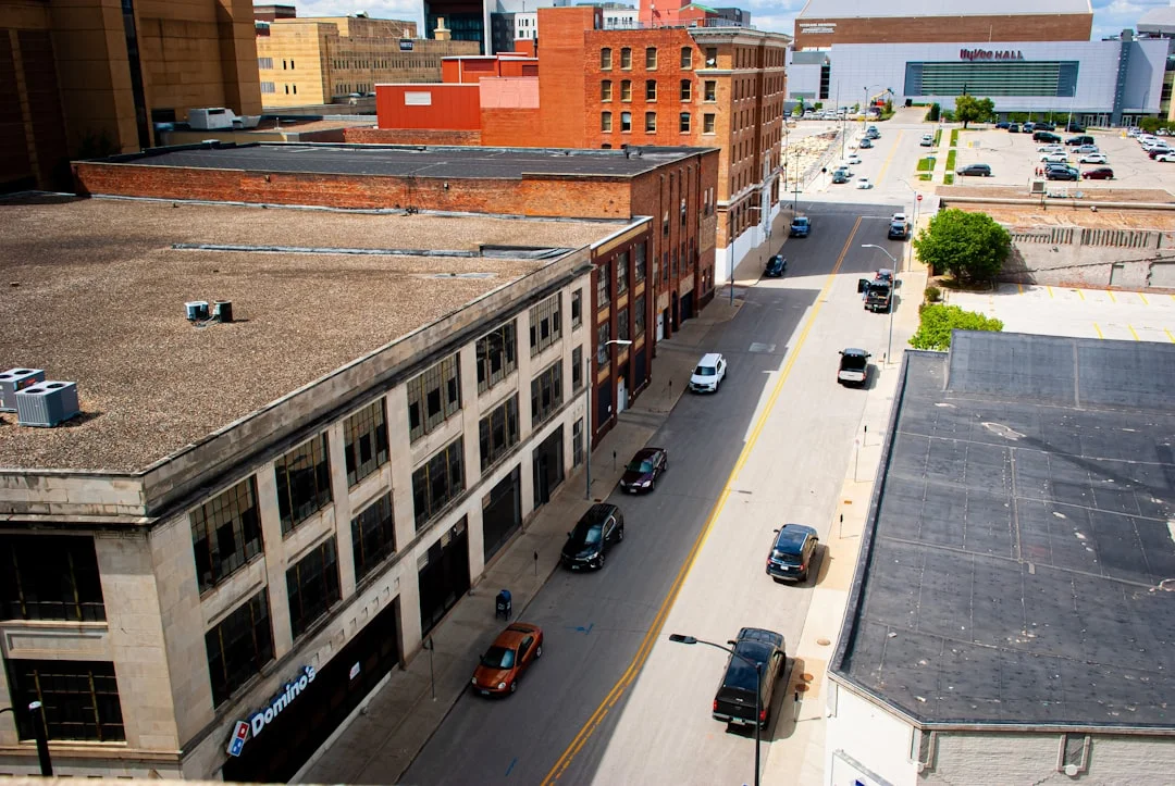 Des Moines, Iowa city street with downtown buildings and late-afternoon light, Iowa state capitol visible in the distance.