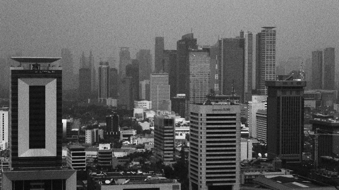 Jakarta skyline at dusk with illuminated towers rising above a tropical city.
