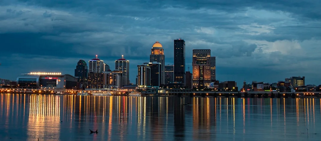 Louisville Kentucky city skyline at dusk reflected in the Ohio River, showing the illuminated downtown and bridge lights.