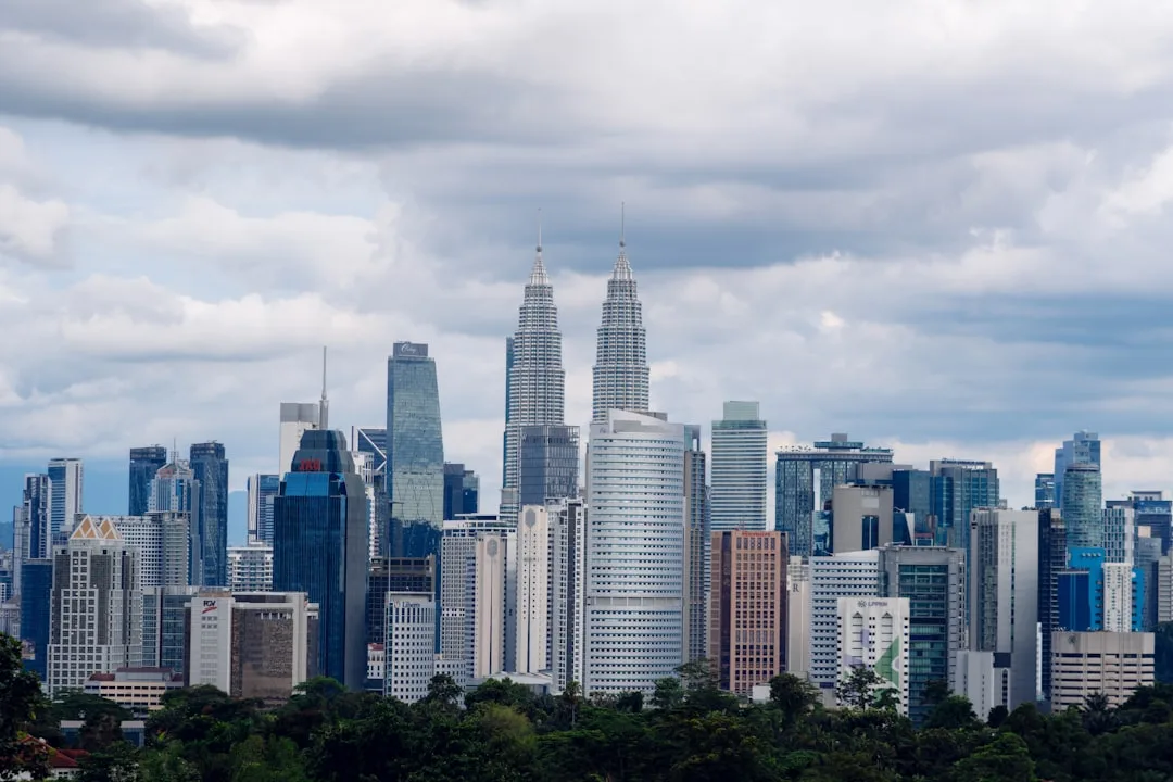 Kuala Lumpur skyline at dusk with the Petronas Towers lit against an orange sky.