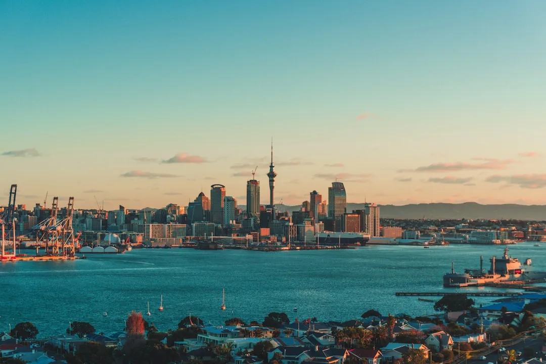 Auckland waterfront at golden hour with the Sky Tower rising behind harbour offices.