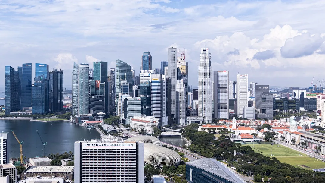 Singapore city skyline seen from the waterfront on a clear morning, with the Marina Bay Sands towers visible in the distance.