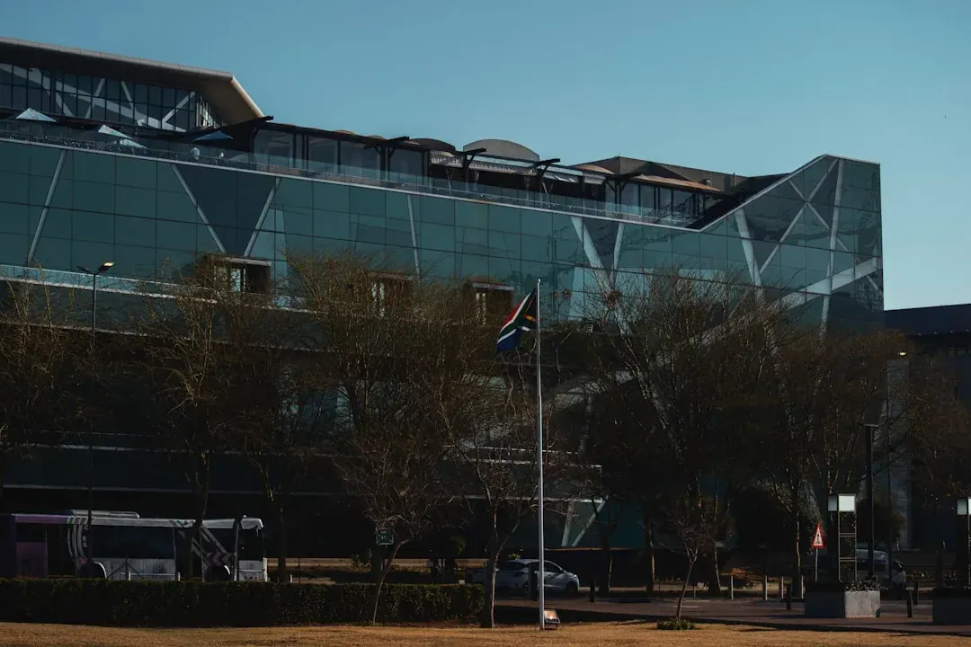 A sunlit co-working office in Johannesburg's Sandton district with desks by tall windows and the skyline beyond.