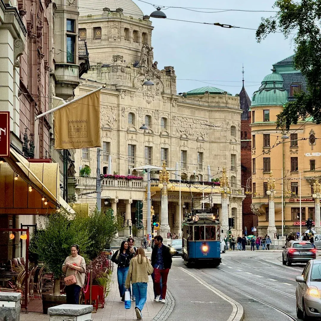 A quiet Stockholm side street in Sodermalm with a corner cafe and bicycles, warm light on pale facades in early autumn.