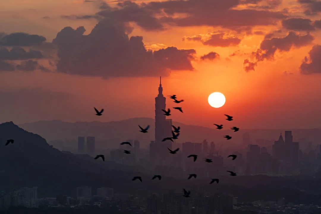 Taipei skyline at golden hour with Taipei 101 rising above the city under a warm sky.