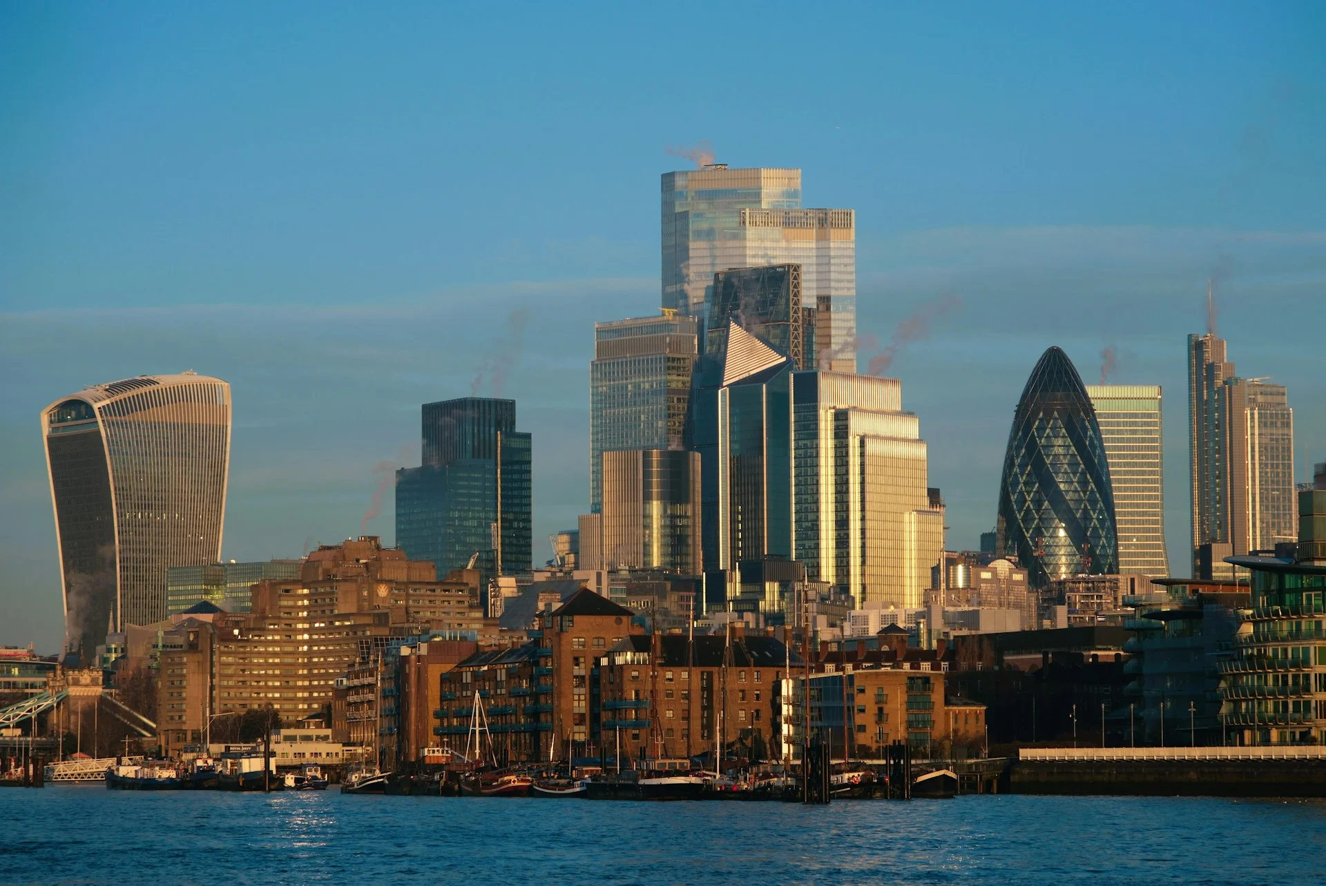 A view of central London at golden hour, the Thames in the foreground.