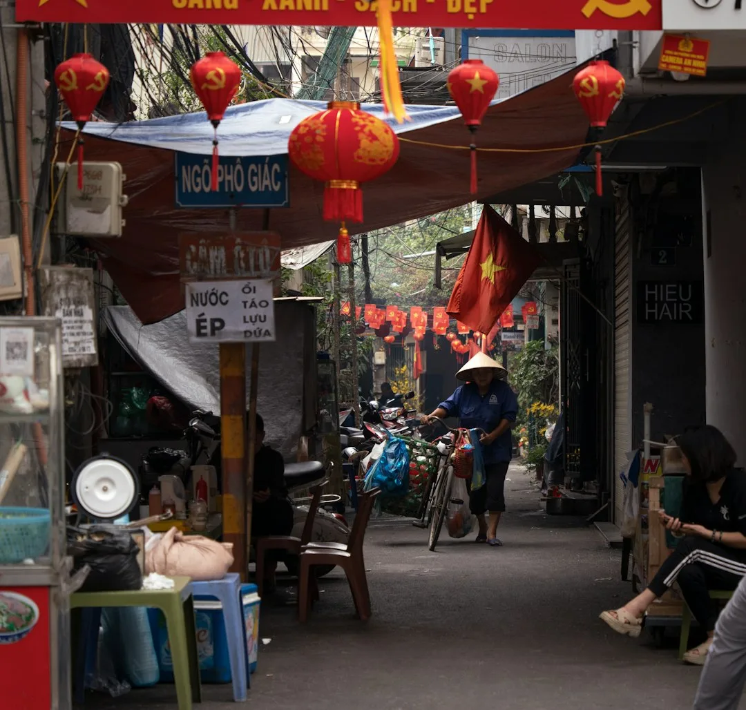 A motorbike weaving through a busy Hanoi street market at dusk.