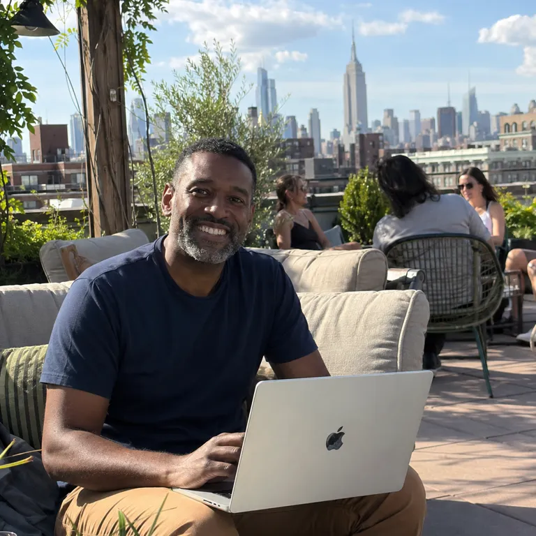 A Teamed traveller working on a rooftop with the New York skyline